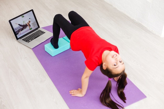 Menina sorridente fazendo exercícios em casa