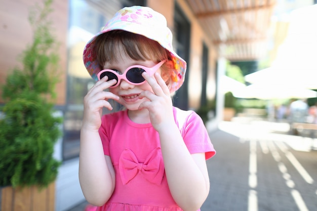 Menina sorridente feliz no retrato ao ar livre de óculos de sol