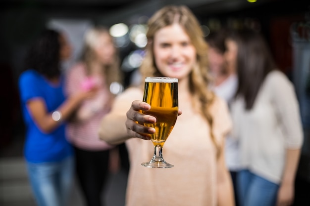 Menina sorridente, mostrando uma cerveja com as amigas