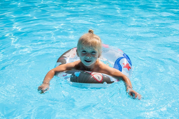 Menina sorridente nada com um anel inflável na piscina