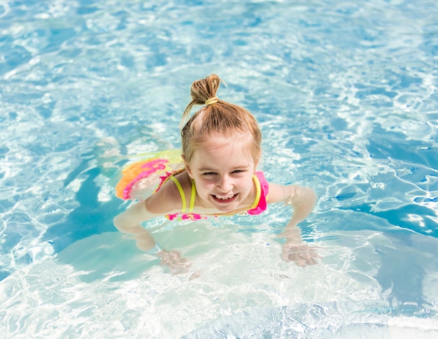 Menina sorridente nadar na beira da piscina