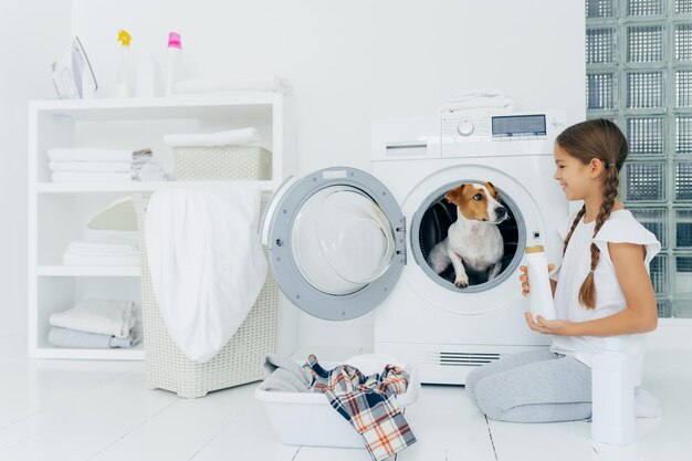 Foto menina sorridente olhando para o cachorro na máquina de lavar