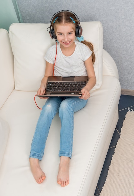 Menina sorridente, ouvindo algo com fones de ouvido Olha para a câmera