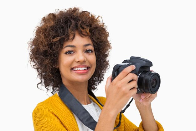 Menina sorridente pegando uma foto e olhando câmera