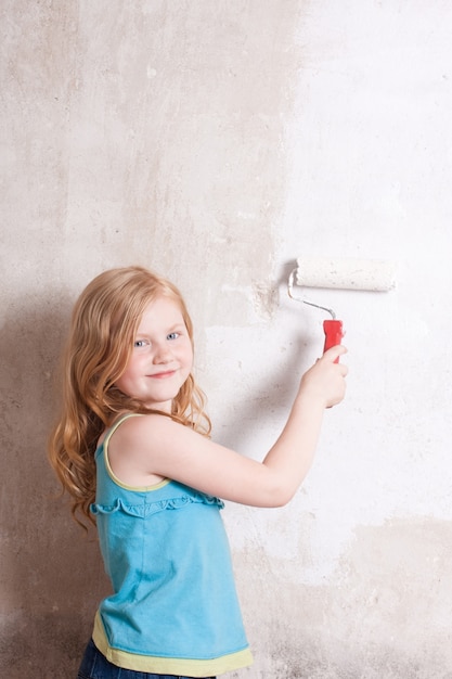 Menina sorridente pintando a parede