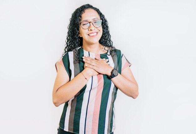 Menina sorridente positiva com as mãos no peito Pessoas gratas com as mãos no peito Jovem grata sorrindo com as mãos no peito isoladas