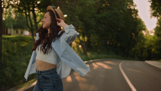 Menina sorridente rindo no parque de verão Closeup mulher feliz virando-se em câmera lenta ao ar livre Menina alegre andando com smartphone na mão na estrada do parque ao pôr do sol