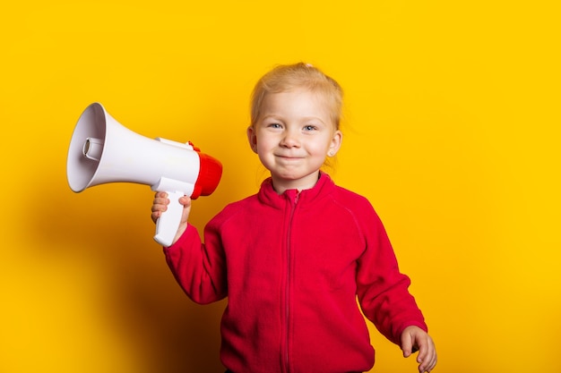 Menina sorridente segurando um megafone em um fundo amarelo brilhante