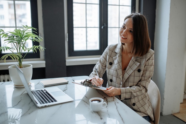 Menina sorridente segurando uma entrevista de emprego e tomando notas no papel