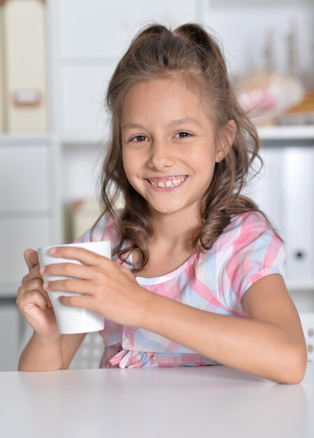 Menina sorridente segurando uma grande xícara de chá
