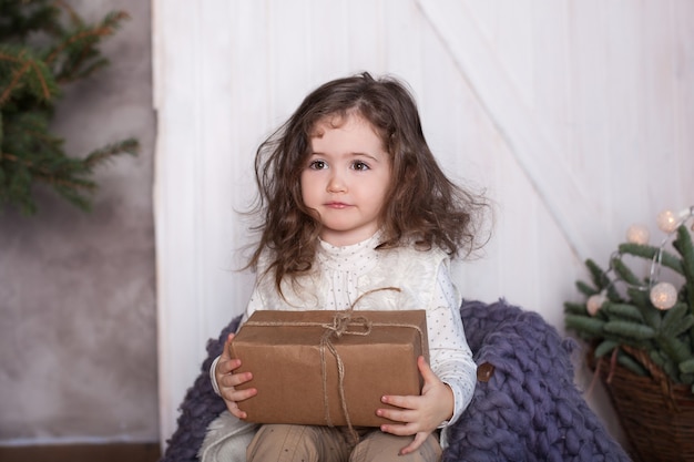 Menina sorridente sentada abrindo presentes de Natal em uma aconchegante sala de estar
