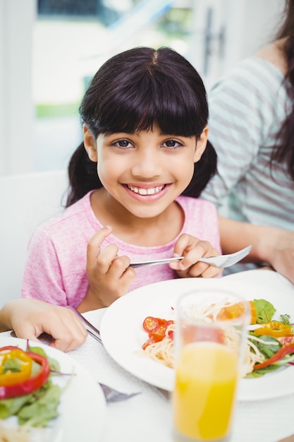 Menina sorridente, sentado na mesa de jantar