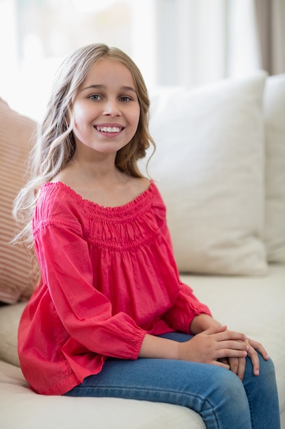 Menina sorridente, sentado no sofá na sala de estar