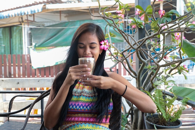 Menina sorridente tomando uma chávena de café com uma flor