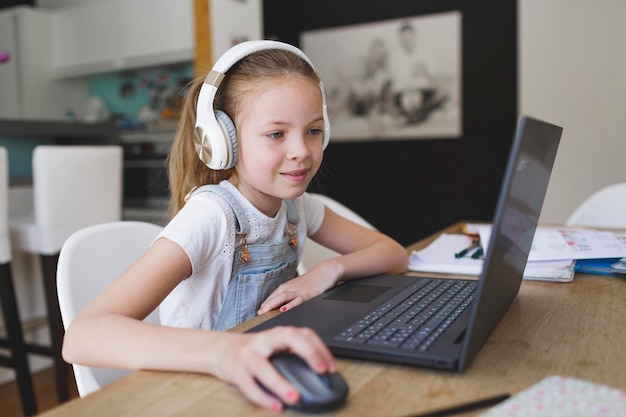 Menina sorridente usando laptop sentada em casa