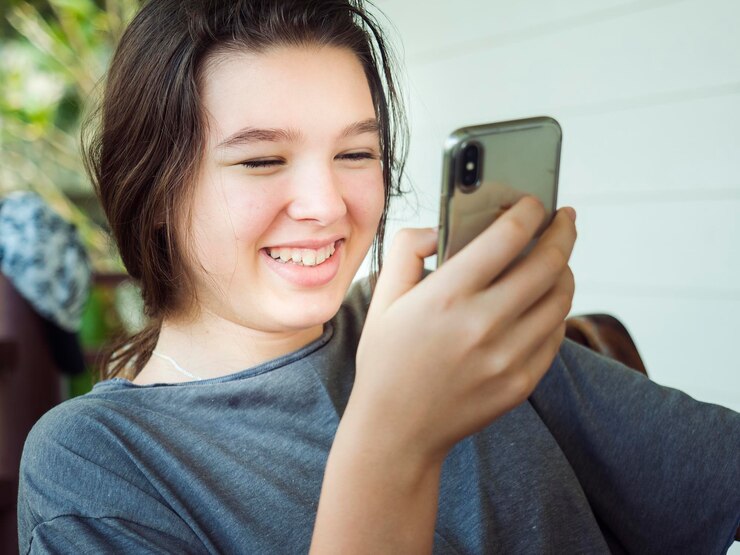 Foto menina sorridente usando telefone celular