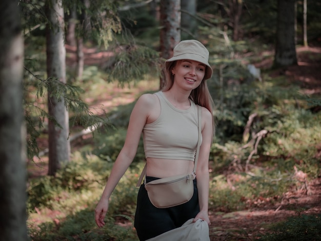 Foto menina sorrindo em pé na floresta e segurando a camisa nas mãos