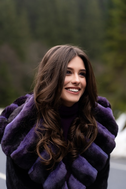 Menina sorrindo para a câmera na floresta de inverno