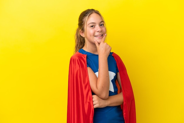 Menina super-herói isolada em fundo amarelo sorrindo