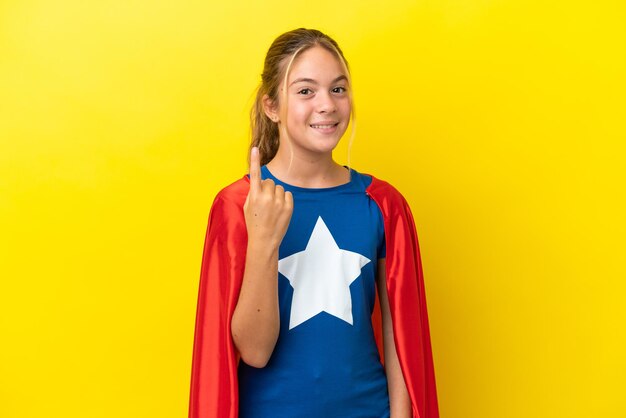 Menina super-heroína isolada em fundo amarelo apontando com o dedo indicador uma ótima ideia
