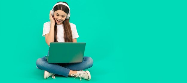 Menina surpresa usa computador sem fio para videochamada ou ouça webinar em fones de ouvido conversando Retrato de menina da escola com pôster horizontal de laptop Cabeçalho de banner com espaço de cópia