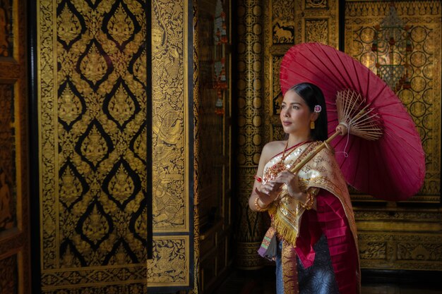 Menina tailandesa das mulheres bonitas que guarda lótus da mão no traje tailandês tradicional com ayutthaya do templo, cultura da identidade de Tailândia.