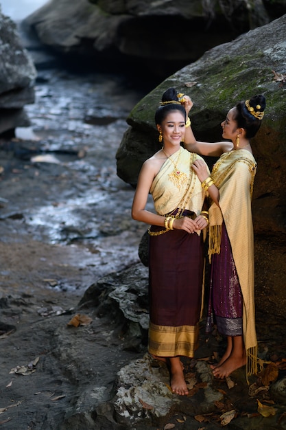 Foto menina tailandesa no traje tailandês tradicional na garganta da pedra da cachoeira, cultura da identidade de tailândia.