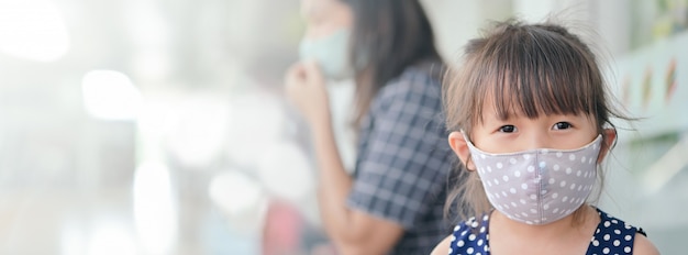 Menina tem máscara de tecido para se proteger de coronavírus, novo estilo de vida normal após surto de covid-19