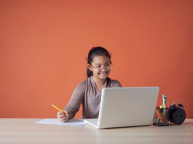 Menina tendo on-line estudando com o laptop em casa.