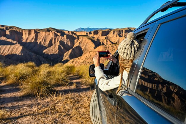 Foto menina tirando fotos da paisagem do deserto pela janela do carro