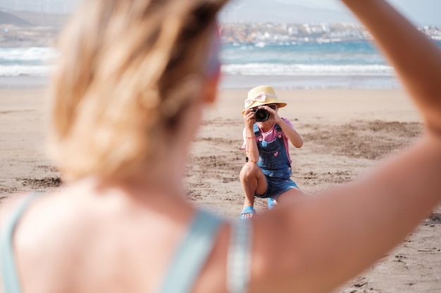 Menina tirando uma foto de sua mãe em um dia na praia juntos Conceito de vínculo de maternidade