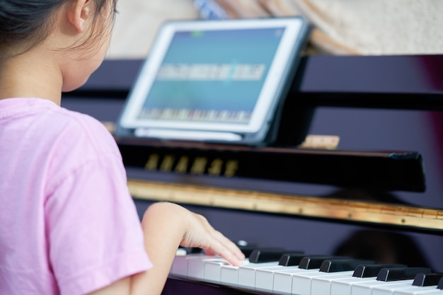 Menina toca teclas de piano em casa