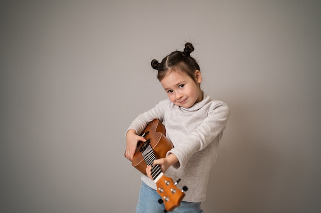 Menina toca ukulele desenvolvimento criativo na educação musical infantil desde a infância ensinando música online em casa