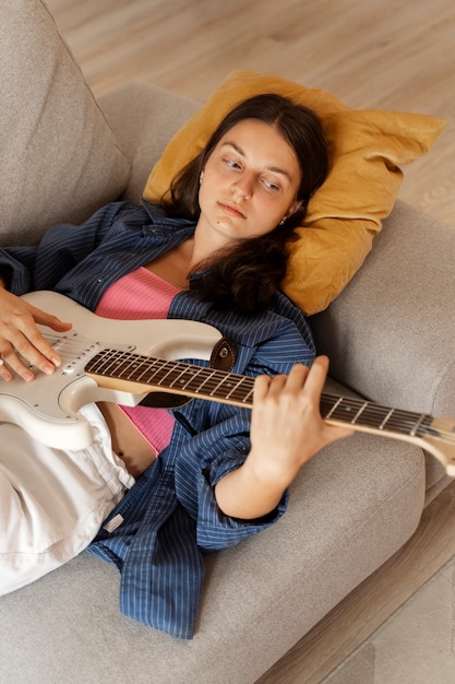 Foto menina tocando guitarra em casa vista superior