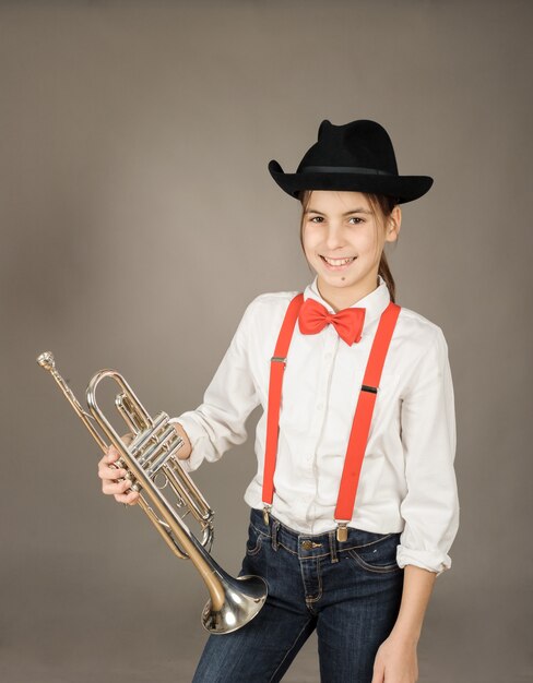 Foto menina tocando trompete em cinza