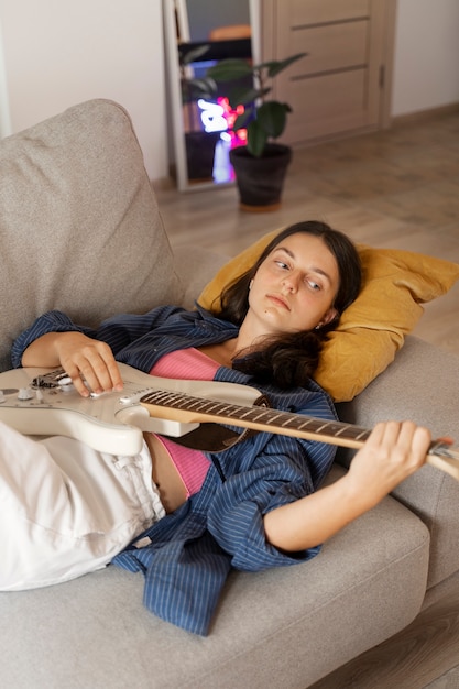 Foto menina tocando violão em casa alto ângulo