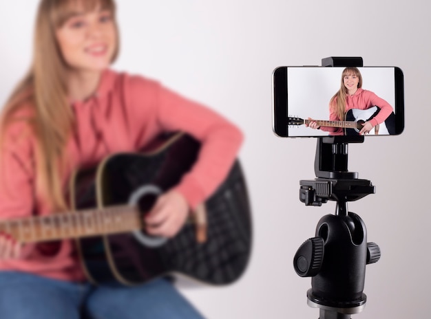 Menina tocando violão para compartilhá-lo nas redes sociais