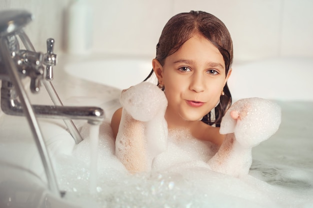 menina toma banho e brinca com espuma no banheiro.