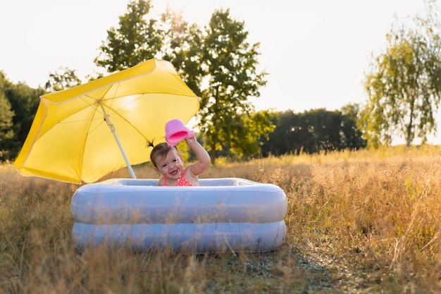 Menina toma banho em uma piscina inflável.