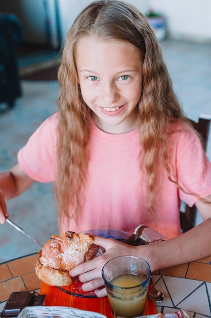 Menina tomando café da manhã no café ao ar livre