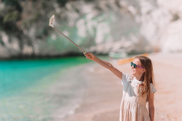 Menina tomando selfie por seu smartphone na praia.