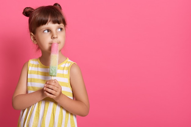 Menina tomando sorvete e olhando sonhadoramente para o lado