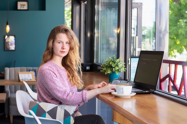 Menina trabalha para um laptop no café