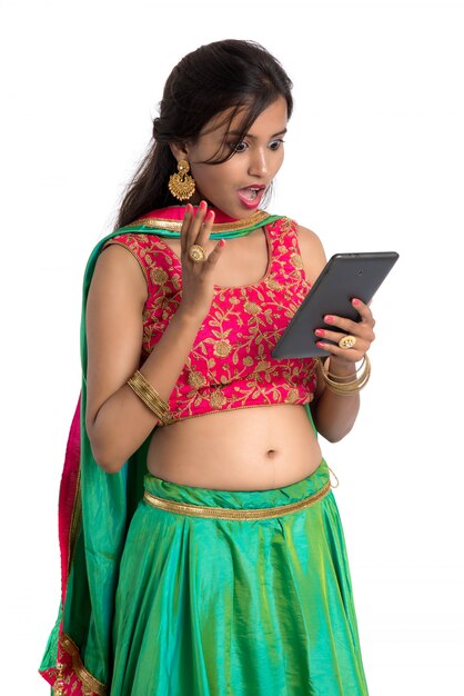 Menina tradicional indiana jovem usando um telefone celular ou smartphone isolado em um branco