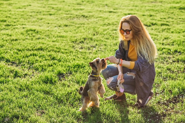 Menina treinando um cachorro pequeno no parque