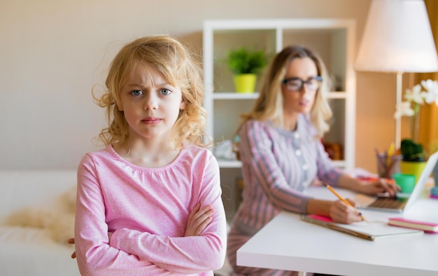 Menina triste ao lado de sua mãe trabalhadora