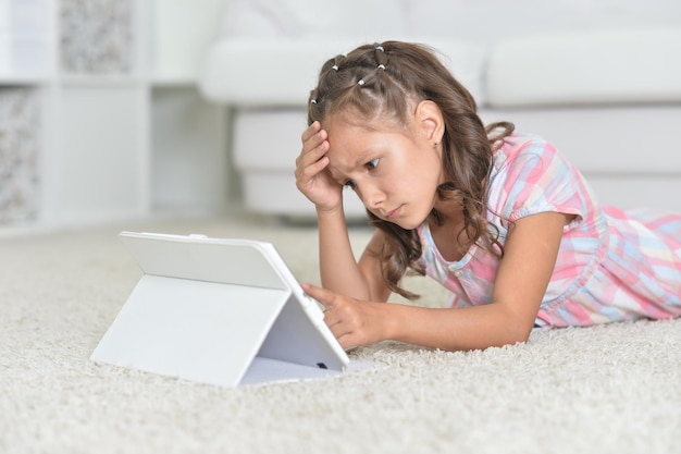 Menina triste com tablet digital no chão