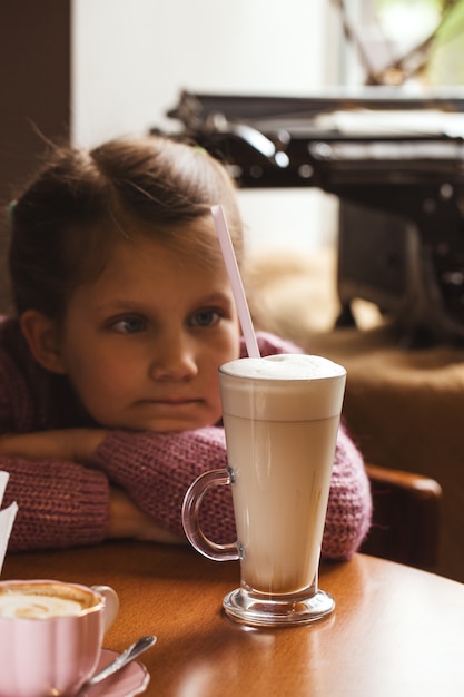 Menina triste com um copo de cacau