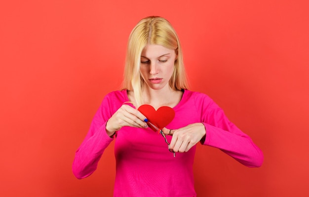 Menina triste corta coração vermelho por tesoura par diverge quebrando relações brigas e divórcio