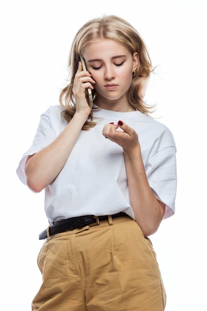 Menina triste fala ao telefone Um adolescente de calça bege e camiseta branca Frustração e más notícias Fundo branco Vertical